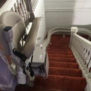 Stairlift parked at top step, seat folded.