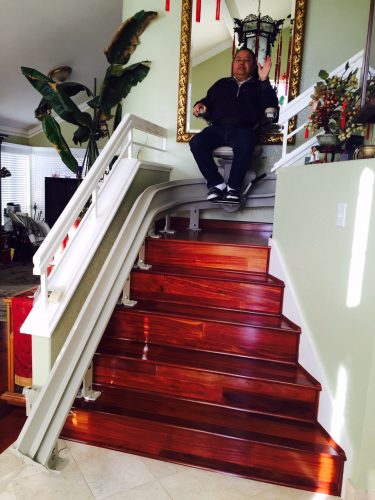 Client Fabricante descending seated in stairlift.
