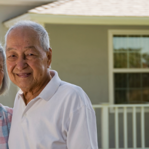 Senior couple standing outside in front of their home.